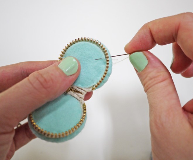 sewing the felt-covered button parts to the zipper on the macaron zipper pouch